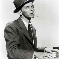 Black-and-white photo, movie still, of Frank Sinatra at piano from film "Pal Joey", no place, no date, ca. 1957.