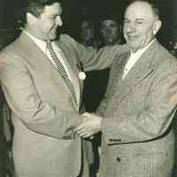 B+W photo of Nathan Marcus, right, of Marcus Jewelers shaking hands with Mayor John Grogan at its Grand Opening, Hoboken, April 3, 1954.