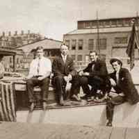 Sepia-tone photo of members of the Active Boat Club on a boat at a Hoboken dock, n.d., ca. 1900-1910.