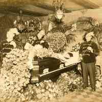 Sepia-tone photo of a funeral bier with an open casket at the Hudsonia Club, Hoboken, no date, ca. 1920.