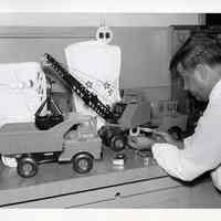 B+W photo of Frank Rizzuli performing measurement on a Nylint toy truck in U.S. Testing Co. lab, Hoboken, n.d., ca. 1975-1980.