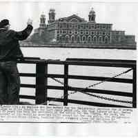 B+W photo of employee on last ferry from Ellis Island waving goodbye as it closed, N.Y. harbor, Nov. 12, 1954.