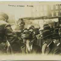 Sepia-tone photo of former President Theodore Roosevelt examining his luggage at Hamburg-American Lines pier in Hoboken, March 22, 1909.