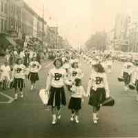 B+W photo of A.J. Demarest High School cheerleaders and band marching on Washington St. after winning a football game, Hoboken, 1950.