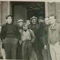 B+W group photo of "On the Waterfront" filming in Hoboken: group of ten men near large building opening, Hoboken, no date, ca. late 1953-early 1954.