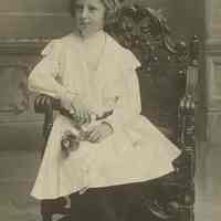 Photo of Florence Miller, ca. 10 years old, posing in a chair at the photographer