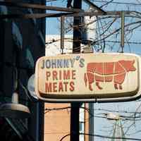 Color photo of a hanging sign for Johnny