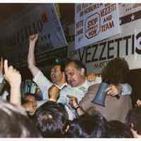 Color photo of mayoral candidate Tom Vezzetti with supporters in front of his campaign headquarters on election night, Hoboken, [June 11, 1985].