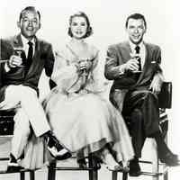 Black-and-white photo, movie still, of Frank Sinatra, Bing Crosby & Grace Kelly posed on bar stools, film "High Society", no place, no date, ca. 1952.