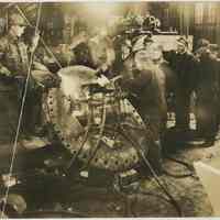 Sepia-tone photo of workers using torches on a large ship fitting in a shop at the W. & A. Fletcher shipyard, Hoboken, no date, ca. 1925.