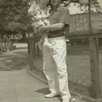 Digital image of B+W negative image of Anthony Durstewitz? (Senior) in a park holding a baby, Hoboken. no date, circa 1938-1940.