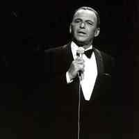 Black-and-white photo of Frank Sinatra Frank Sinatra in tuxedo on stage at Carnegie Hall with microphone, New York, no date, ca. 1963.