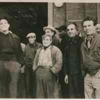 B+W group photo of "On the Waterfront" filming in Hoboken: group of seven men near large building opening, Hoboken, no date, ca. late 1953-early 1954.