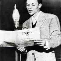 Black-and-white copy photo of a young Frank Sinatra singing at a microphone with sheet music for "That Old Black Magic", no place, no date, ca. 1945.