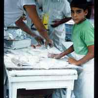 Color slide of a young boy helping make food at a street fair.