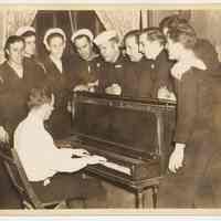 Sepia-tone photo of sailors gathered at a piano and singing, Hoboken Y.M.C.A., Hoboken, n.d., ca. 1942-1946.