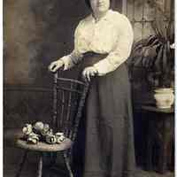 Sepia-tone photos, 2, of young different woman posed with chair in studio with interior backdrop, Hoboken, n.d., ca. 1904-1918.