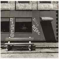 B+W photo of a street-level building front with three painted "Disco" signs, Hoboken, no date, [1976].