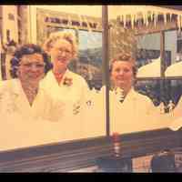 Color slide of three women looking through a window.