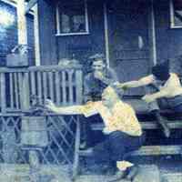 Digital image of photo of three men seated on porch steps engaging in horseplay, no place (probably not Hoboken), no date, circa late 1910-1920.