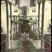 Lantern slide, color, of a synagogue interior with floral decorations, used for promotional display in Hoboken, no date, ca. 1920.