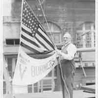 B+W photo of a man raising an American flag and V Burners pennant, Hoboken, no date, ca. 1942-45.