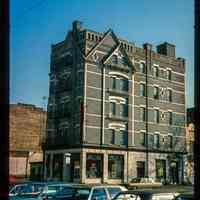 Color slide of eye-level view of front and side façades with fire escape at 77 Hudson Street on the NE corner of Hudson Place occupied by the Victor Hotel