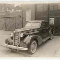 Sepia-tone photo of automobile parked on sidewalk outside commercial garage, Hoboken, n.d., probably 1938 (probable car license date.)