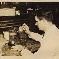 Sepia-tone photo of Robert Smith performing chemical test at work bench, United Testing Company, Hoboken, N.J. No date, circa 1940-1945.