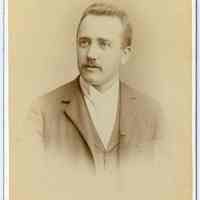 Cabinet photo of a young man with mustache posed in photographer