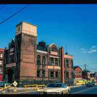 Color slide of eye-level view of the Hoboken Fire Department Engine Company No. 3 (Truck 2) fire station façade at 501 Observer Highway looking E at the juncture with Newark and showing the Jefferson Packing Co. on the corner of Jefferson and Newark