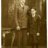 Sepia-tone photo of man & boy posed in studio with church backdrop, Hoboken, n.d., ca. late 1910s through 1920s.