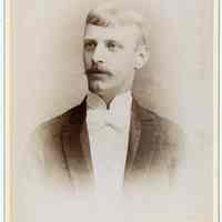 Cabinet photo of a young man with mustache posed in photographer