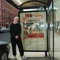 Color photos, 2, of Jim Hans with 100 Hoboken Firsts exhibit bus shelter marquee sign, Hoboken, March 18, 2006.