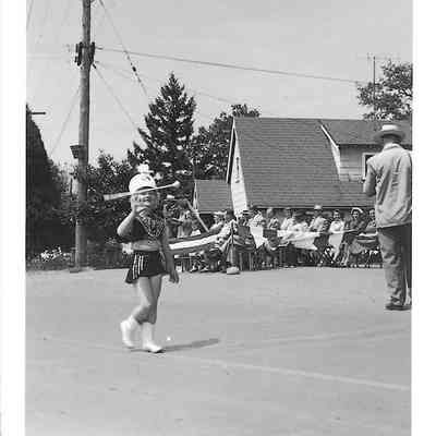 Pat Tiljestrom in Majorette uniform twirling baton, possibly in parade