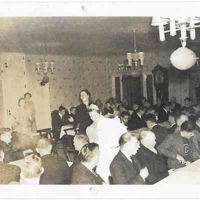 Woman standing in a crowded room of people sitting at tables during the Football banquet at Lakewood Terrace