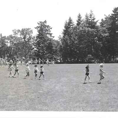 Majorette leading young girls with batons through a field