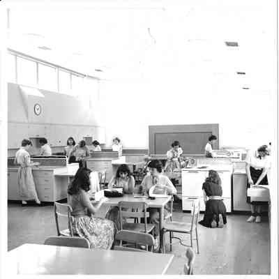Thirteen young people in what appears to be home ec working at various stations in a room at Hudtloff Jr High with a slanted ceiling