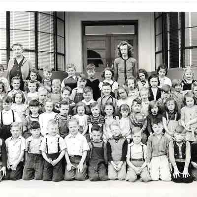 Class photo, 5 lines of children, two teachers in front of building