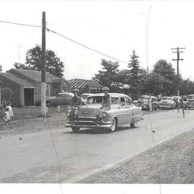 Two boys from Parkland Round Up Royalty riding on hood of car during parade