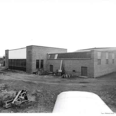 North elevation showing hangar doors as seen from the view of plane whose wing can be seen in front of photo