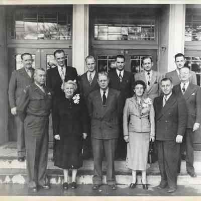 Various government and military officials standing with Clover Park Jr-Sr High School staff members standing on the exterior steps of Clover Park Jr-Sr High School, 1948