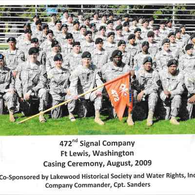 472nd Signal Company posing on bleachers with company flag at front