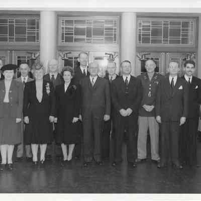 Photograph of various government and military officials standing with Pearl A. Wanamaker and A. G. Hudtloff inside of Clover Park hr-Sr High School doorway
