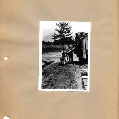 Men loading wheelbarrow with cement at Lake City School construction site