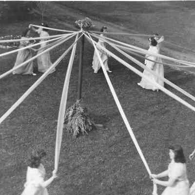 Girls in white dancing at the ends of Maypole strands at Vistiation Villa