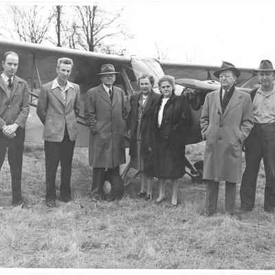 Menir, Earl Aynder, Aerall, Iva A. Mann, Nellie Wootan, A. G. Hudtloff, and Jaler standing in front of airplane