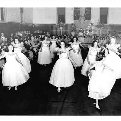 Girls in white dresses appearing to do a ballet performance in front of a small crowd at Visitation Villa