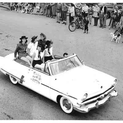 Five girls in cowboy outfits riding in car during Tillicum 4th of July parade