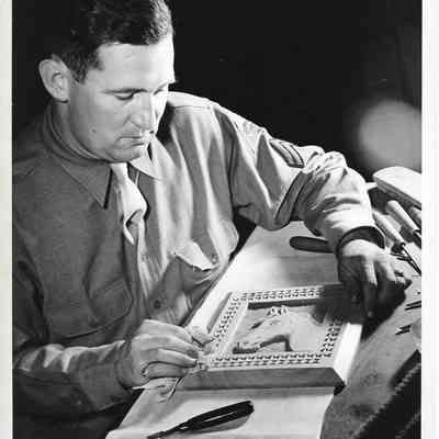 Military member polishing carved wooden horse in frame